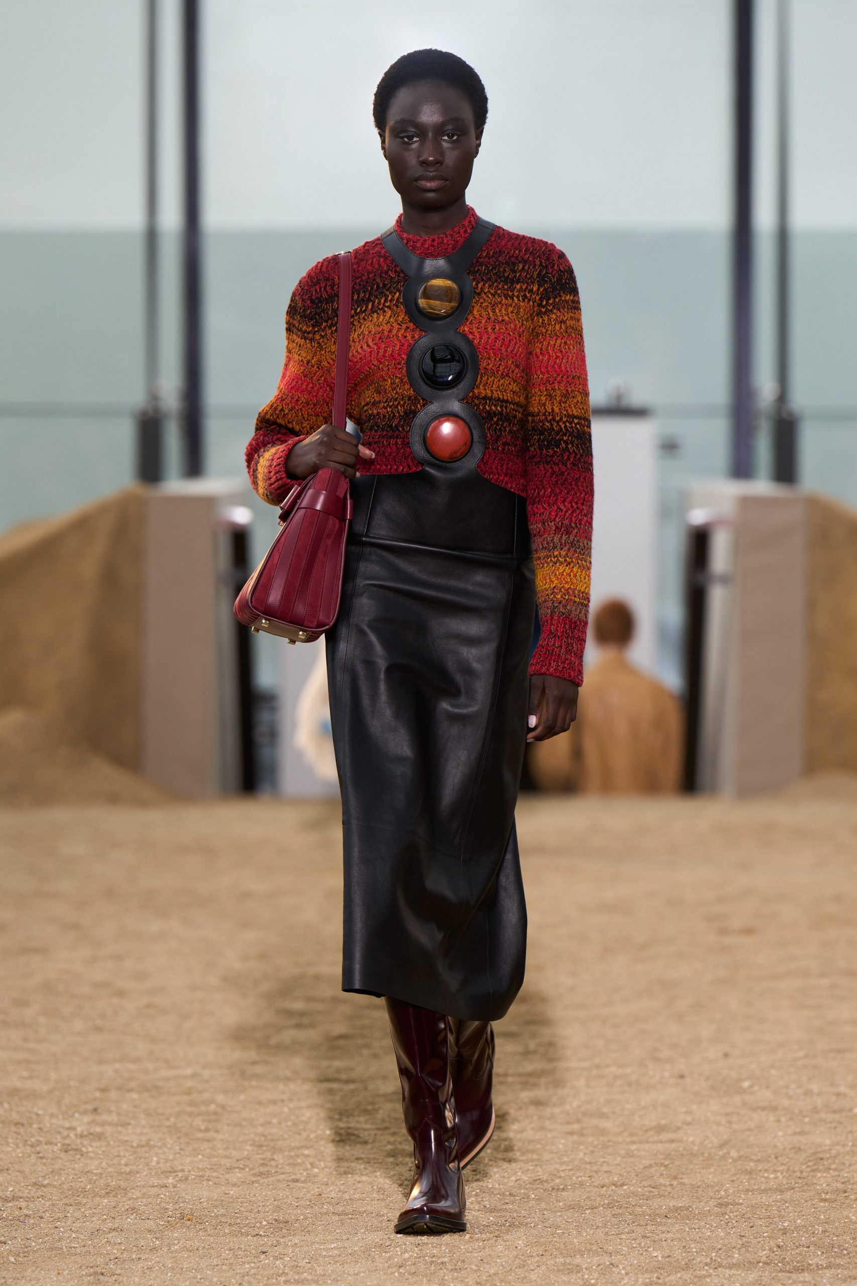 A model wears a knit top with a leather skirt and accessories