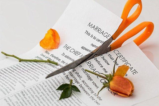 orange scissors and roses cutting a marriage lisece in half