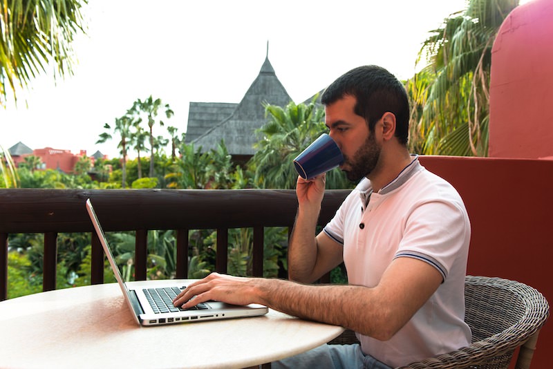 man working with his laptop on a hotel terrace