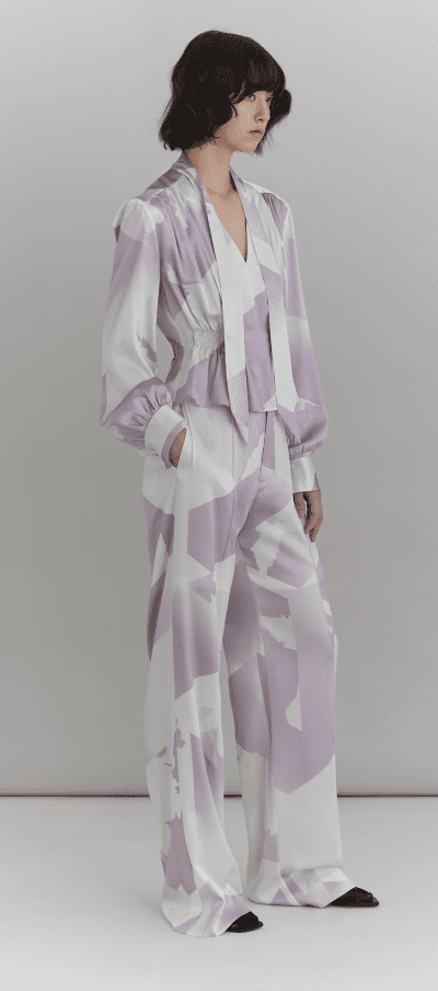 Model wearing blouse and trouser with lilac shapes