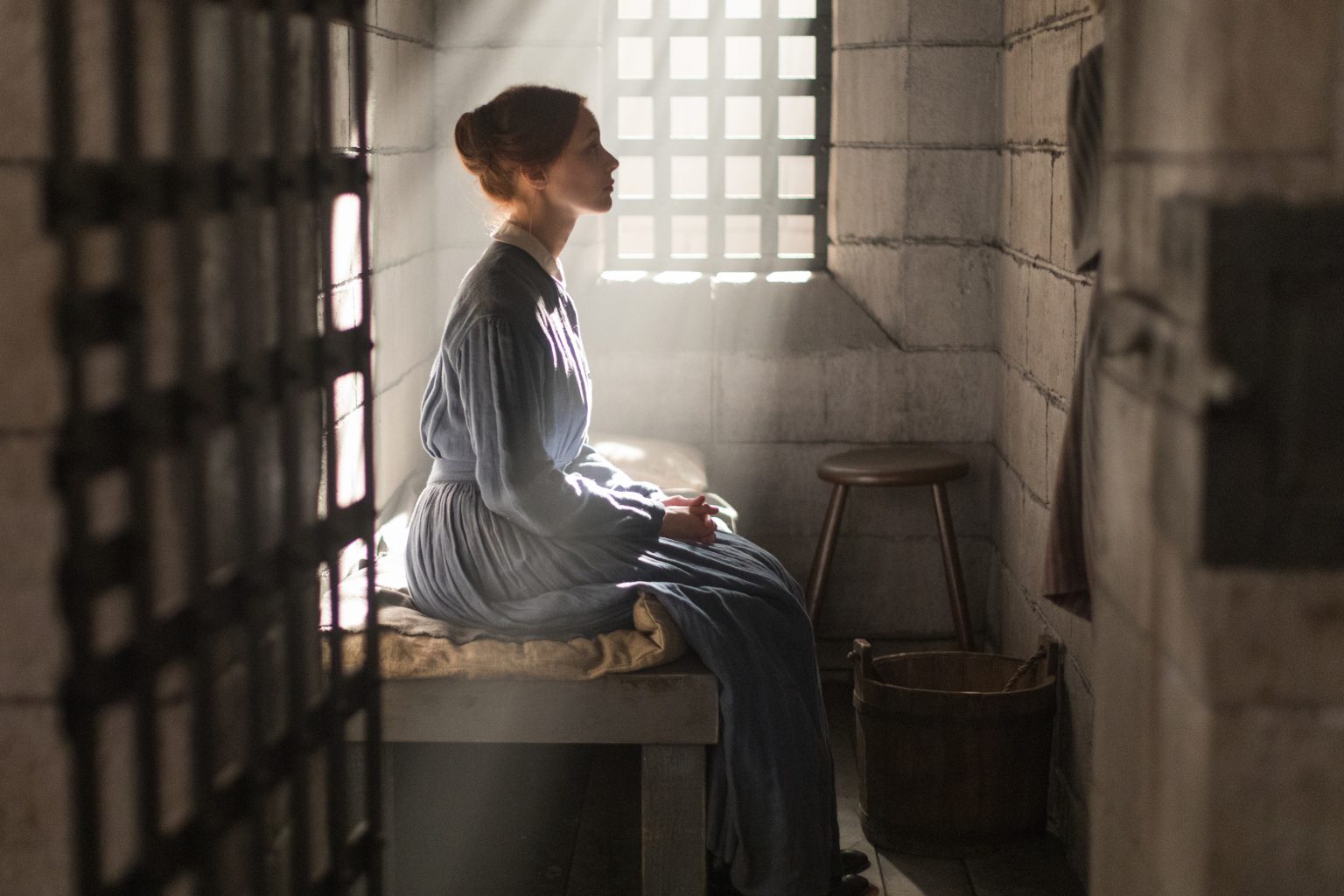 A woman sits in a prison cell