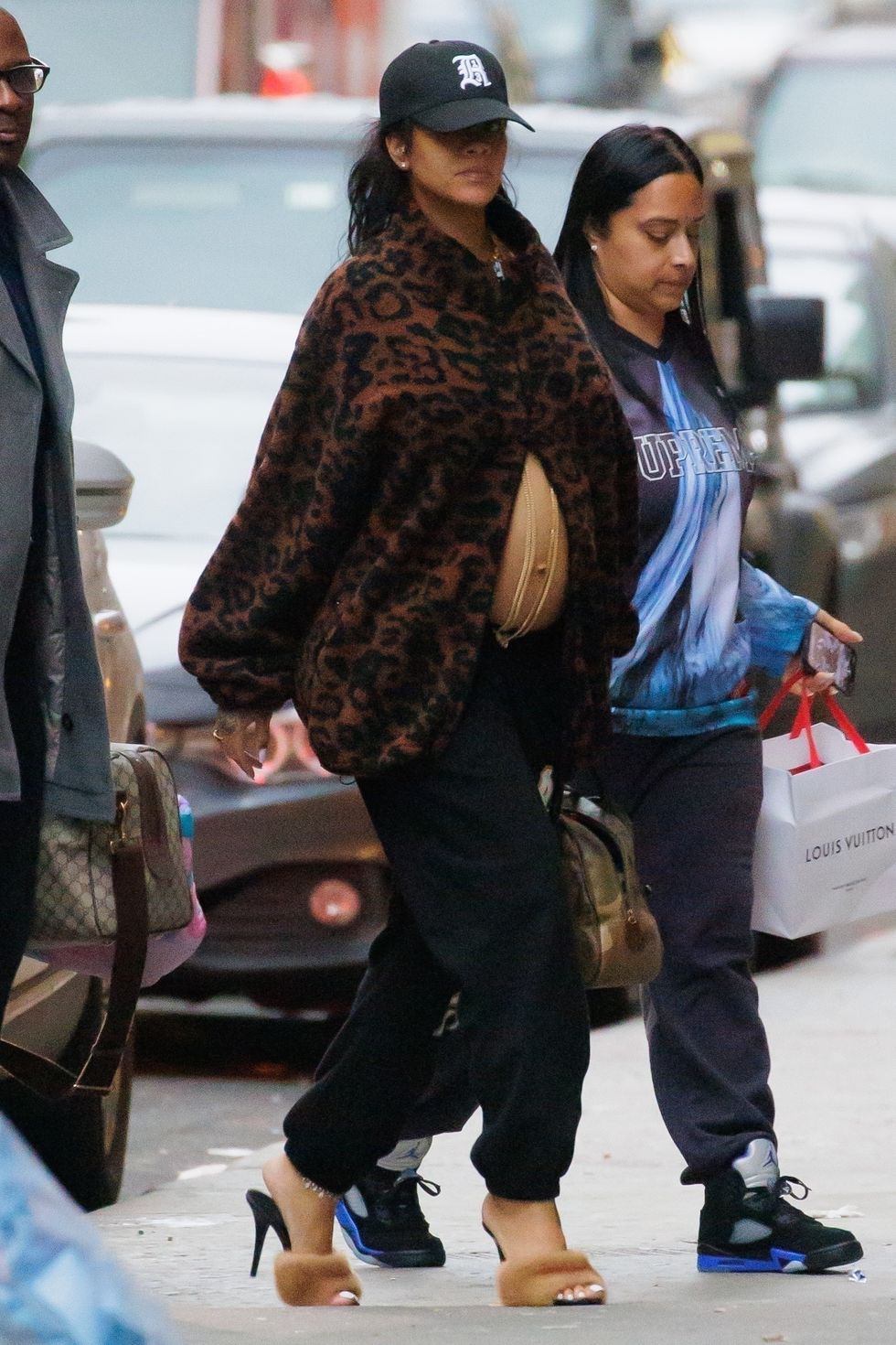 Rihanna in an unzipped leopard print coat, black pants, and mink-trimmed shoes