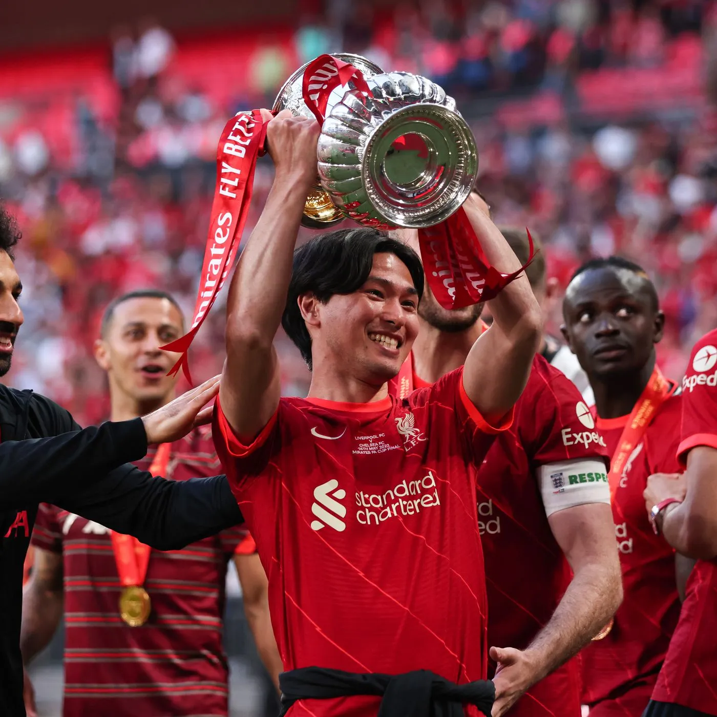 Takumi Minamino celebrates with the FA Cup trophy.