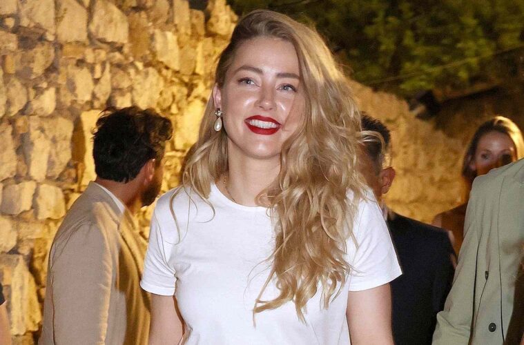 Amber Heard attending Italian Film Festival in white shirt, long blonde hair swept to the side and red lipstick on with large pearl drop earrings