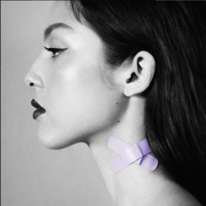 Olivia Rodrigo's single cover for 'Vampire'. She's facing left wearing dark lipstick, winged eyeliner, and her dark hair is pushed back behind her ears. The photo is in black and white except for two lavender bandaids on her neck. They're crossed over each other to make and X shape.