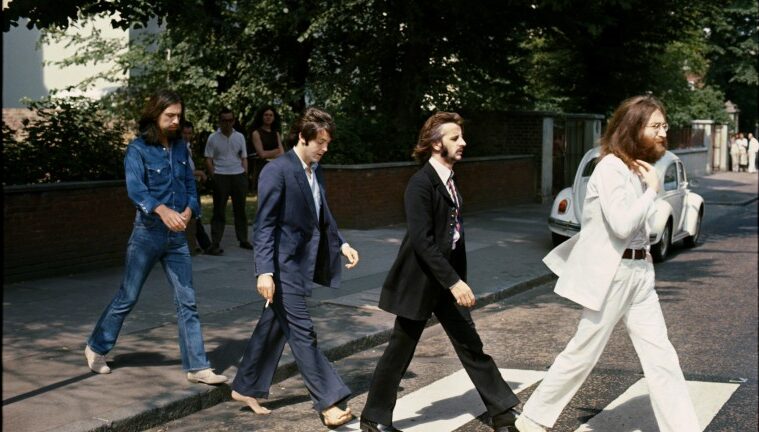 The Beatles Walking a cross walk on Abbey Lane during the day. Position from left to right, George Harrison, Paul McCartney, Ringo Star, John Lennon.