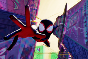 Miles Morales as SpiderMan falling in-between buildings reaching out to the screen