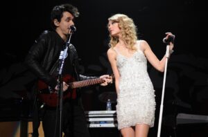 John Mayer and Taylor Swift perform onstage during Z100's Jingle Ball 2009 at Madison Square Garden on December 11, 2009 in New York City. Taylor's wearing a silver beaded dress and has her hair down and tightly waved. John is wearing black leather jacket, shirt and jeans with his hair slicked straight up.