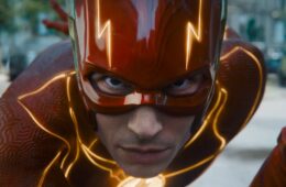 Ezra Miller as the flash posing to run down a city street with yellow lightning lighting his suit