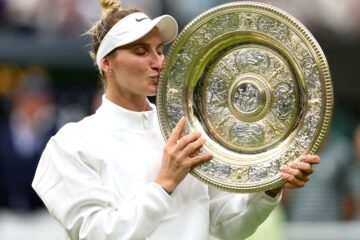 Marketa Vondrousova kissing her trophy on the court after being awarded in Wimbledon.