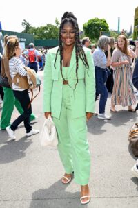 Clara Amfo posing at Wimbledon in a matching mint colored top, blazer and pant with a white bag.