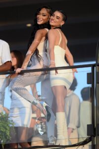 Winnie Harlow and Dixie D'Amelio posing over their shoulders on a balcony at Michael Rubin's Fourth of July White Party