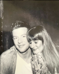 A black and white photo of Lea Michelle cuddled up against Cory Monteith.