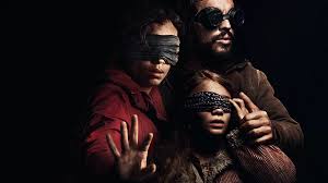 A poster for 'Bird Box Barcelona'. It pictures three of the main characters blindfolded in-front of a black background shadowed.