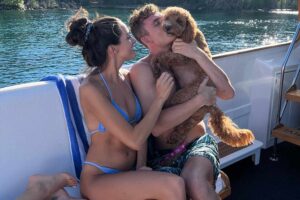 James Kennedy on a boat with his girlfriend kissing his dog Graham Cracker.