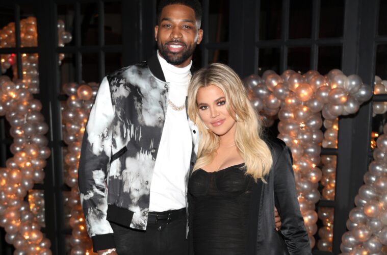 Tristan Thompson (left) posing with his arm around Khloé Kardashian (right) in front of a light up sign of his name
