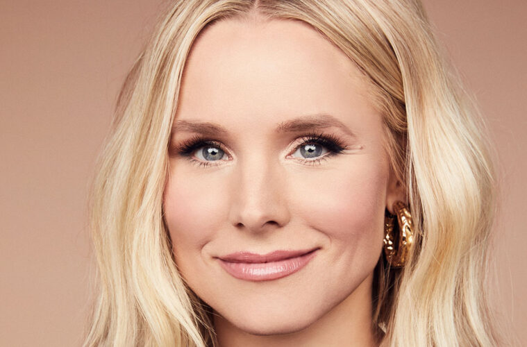 A headshot of Kristen Bell grinning in front if an ombre peach/light pink background.