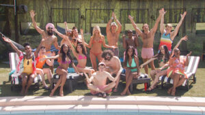 The full cast of season 25 of Big Brother posing happily for a picture by the pool in the backyard of the Big Brother House.