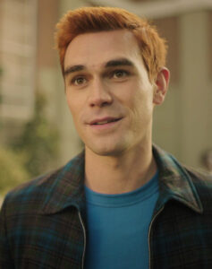Archie Andrews with short, red hair. Wearing a plaid, collared jacket and a blue t-shirt.