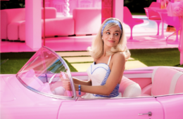 Barbie driving her pink car in Barbie Land looking over her left shoulder