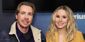 Actors Kristen Bell (right) and her husband Dax Shepard (left) posing on a couch together for photo at SiriusXM Studios in 2019