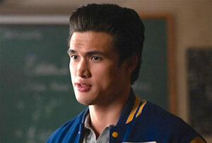 Reggie Mantle standing in a classroom, in front of a chalkboard, wearing his Riverdale letterman jacket