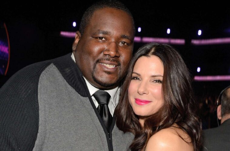 Quinton Aaron (left) smiling for a photo with his 'Blind Side' costar Sandra Bullock (right)