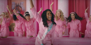 The Barbie's, in pink jumpsuits, celebrating in the courthouse. Issa Rae is showcased as President Barbie