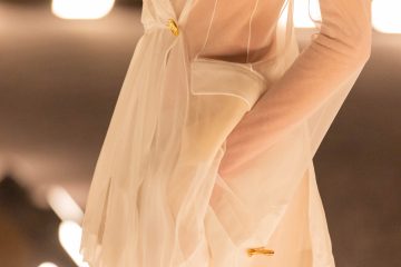 A sheer ivory Schiaparelli suit from the Spring/Summer 2026 runway, featuring a translucent tailored jacket with gold hardware and soft, fluid draping.