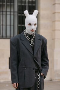 Influencers dressed in statement looks pause outside a Paris Fashion Week venue, searching for the perfect street style photo to share across Instagram and TikTok.