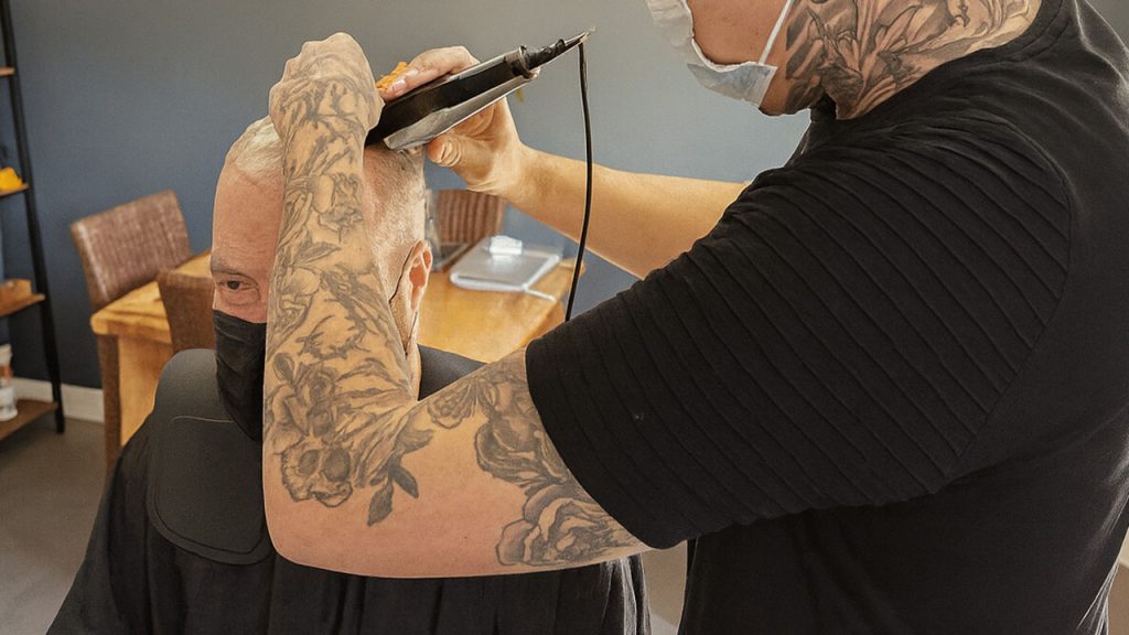 stylist installing a hair system, contributing to hair system cost