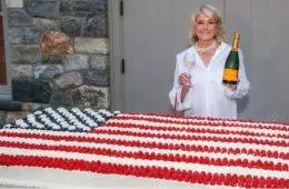 Martha Stewart poses beside a giant American flag cake created for her Founding Father-themed celebration honoring America's 250th anniversary.