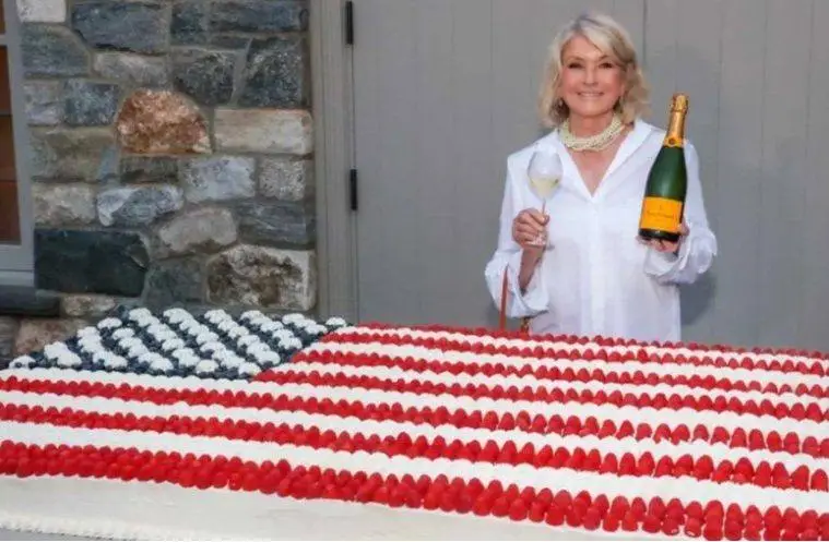 Martha Stewart poses beside a giant American flag cake created for her Founding Father-themed celebration honoring America's 250th anniversary.