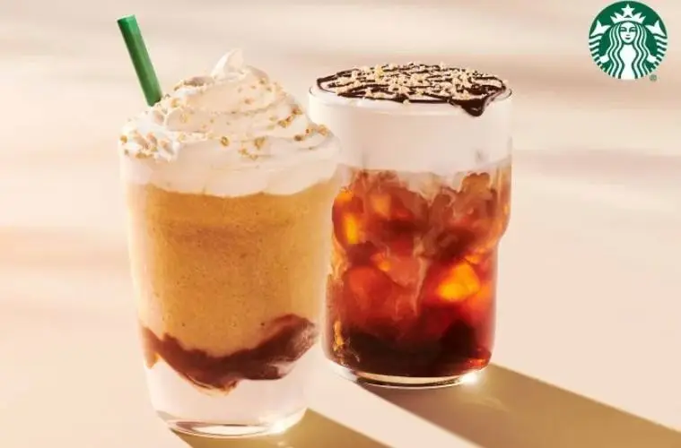 Starbucks' returning S'mores Frappuccino sits beside the new S'mores Cold Brew, both topped with marshmallow-inspired flavors and graham cracker crumbs.