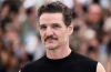 Pedro Pascal posing on the red carpet at the Jackass: Best and Last premiere wearing a dark outfit with purple accents.