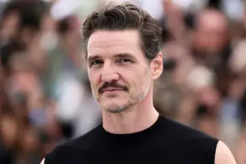 Pedro Pascal posing on the red carpet at the Jackass: Best and Last premiere wearing a dark outfit with purple accents.