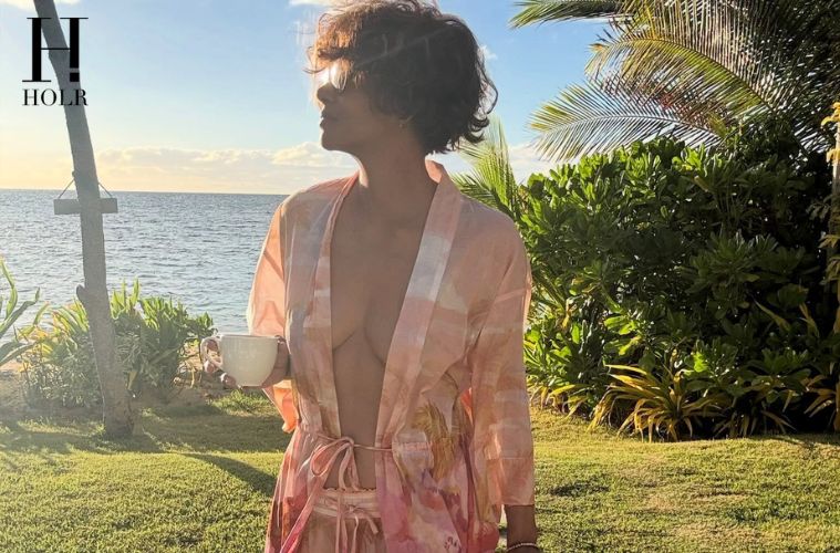 Halle Berry walking along a tropical beach in a pink floral cover-up during her latest Instagram post.