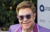 Elton John smiling while raising a glass of his alcohol-free sparkling wine as he celebrates 36 years of sobriety.