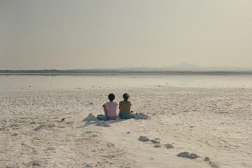 Two women share a quiet moment in The Lion at My Back, reflecting the film's themes of friendship and resilience against the backdrop of Cyprus.