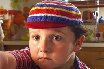 Paulie Litt as Spritle in the 2008 Speed Racer movie, smiling alongside Chim Chim during one of the film's memorable family moments.