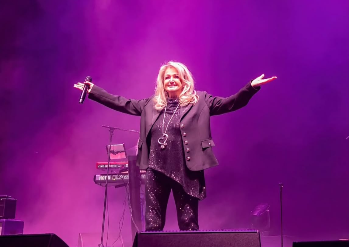 Bonnie Tyler performing on stage during a live concert, celebrating the legendary singer's decades-long career and lasting musical legacy.