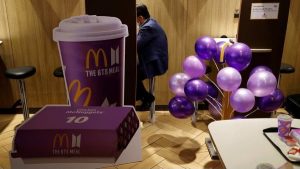 A McDonald's Happy Meal box displayed alongside colorful BT21 collectible character toys inspired by BTS, promoting the limited-time collaboration.