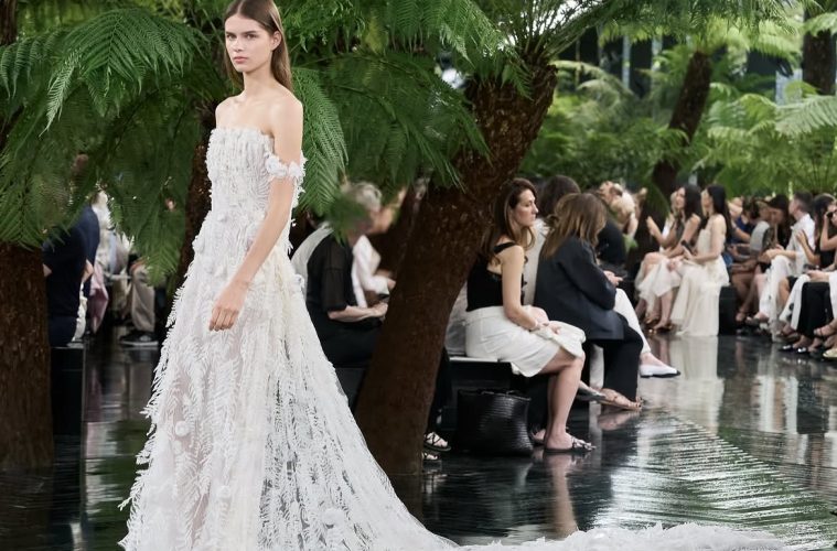 Model wearing Dior Fall/Winter 2026–2027 Haute Couture Look 57, featuring a white silk chiffon ensemble embroidered with cactus flowers and finished with artistic frayed edges.