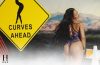Rihanna poses beside a "Curves Ahead" road sign while modeling a floral lace bodysuit for Savage X Fenty.