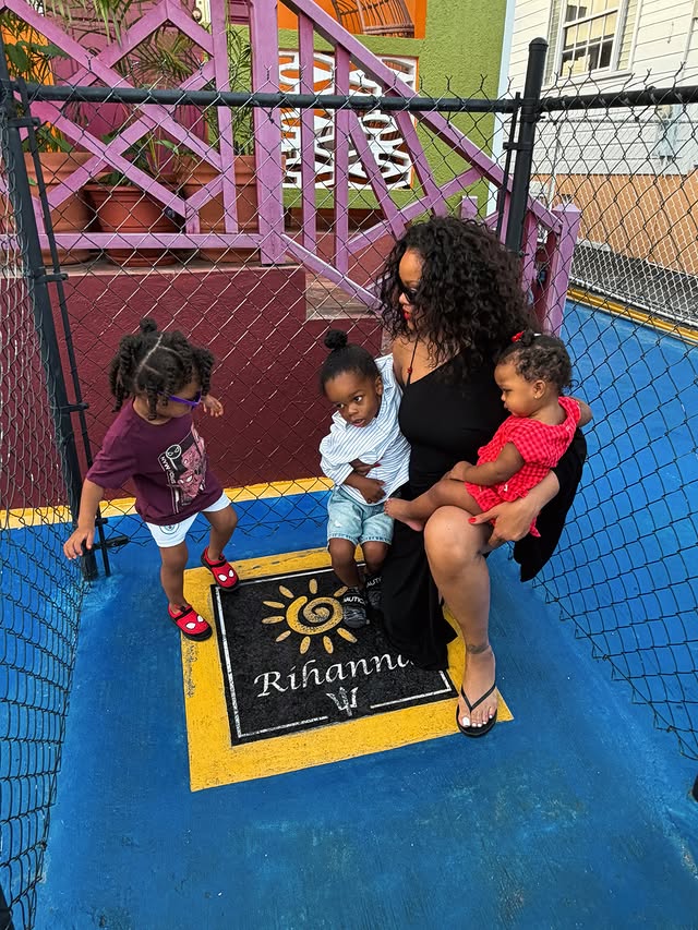 Rihanna stands with her children outside her childhood neighborhood on Rihanna Drive in Barbados.
