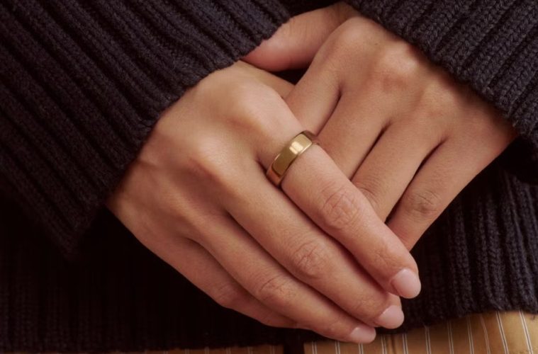 Oura Ring 5 worn alongside gold jewelry, showing its slim design and jewelry-like appearance.