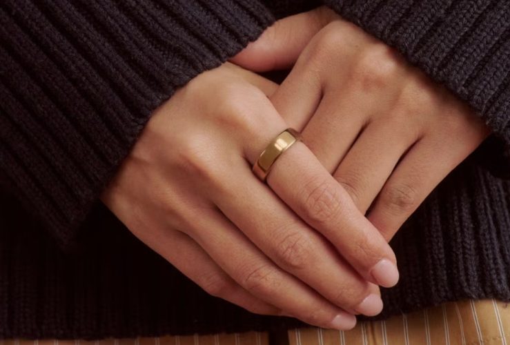 Oura Ring 5 worn alongside gold jewelry, showing its slim design and jewelry-like appearance.