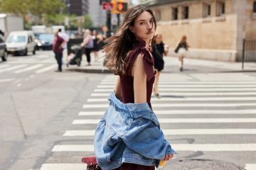 A woman wears a feminine midi dress styled with polished accessories for a modern office outfit.