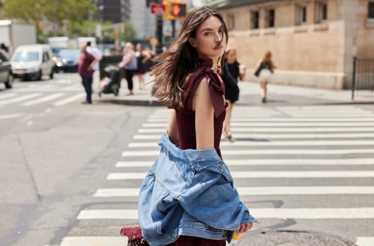 A woman wears a feminine midi dress styled with polished accessories for a modern office outfit.