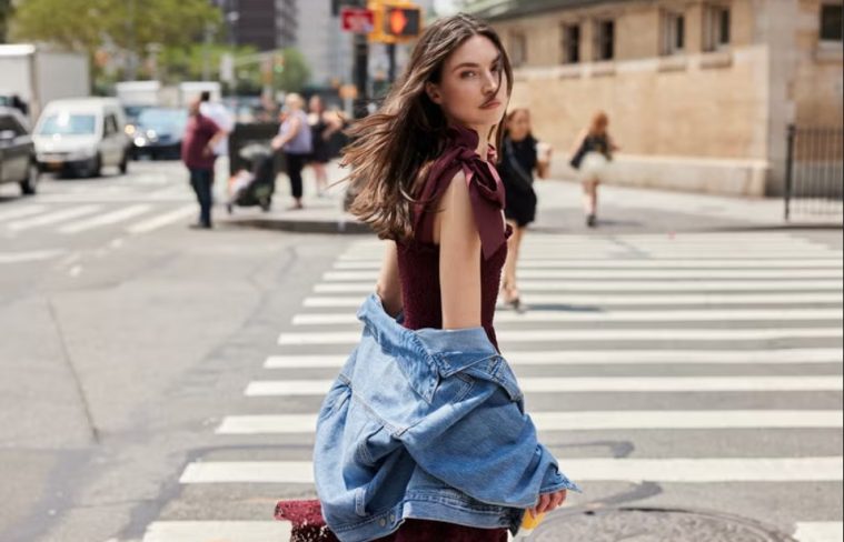 A woman wears a feminine midi dress styled with polished accessories for a modern office outfit.
